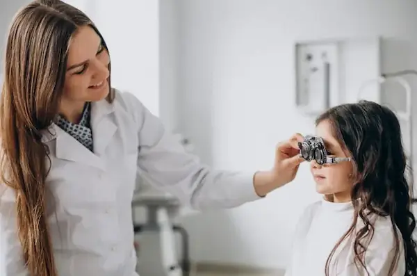 especialista en el cuidado de ojos midiendo la vista de una niña